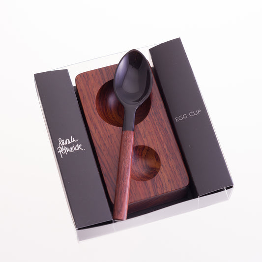 A gift box containing a solid rosewood eggcup with a horn and rosewood egg spoon
