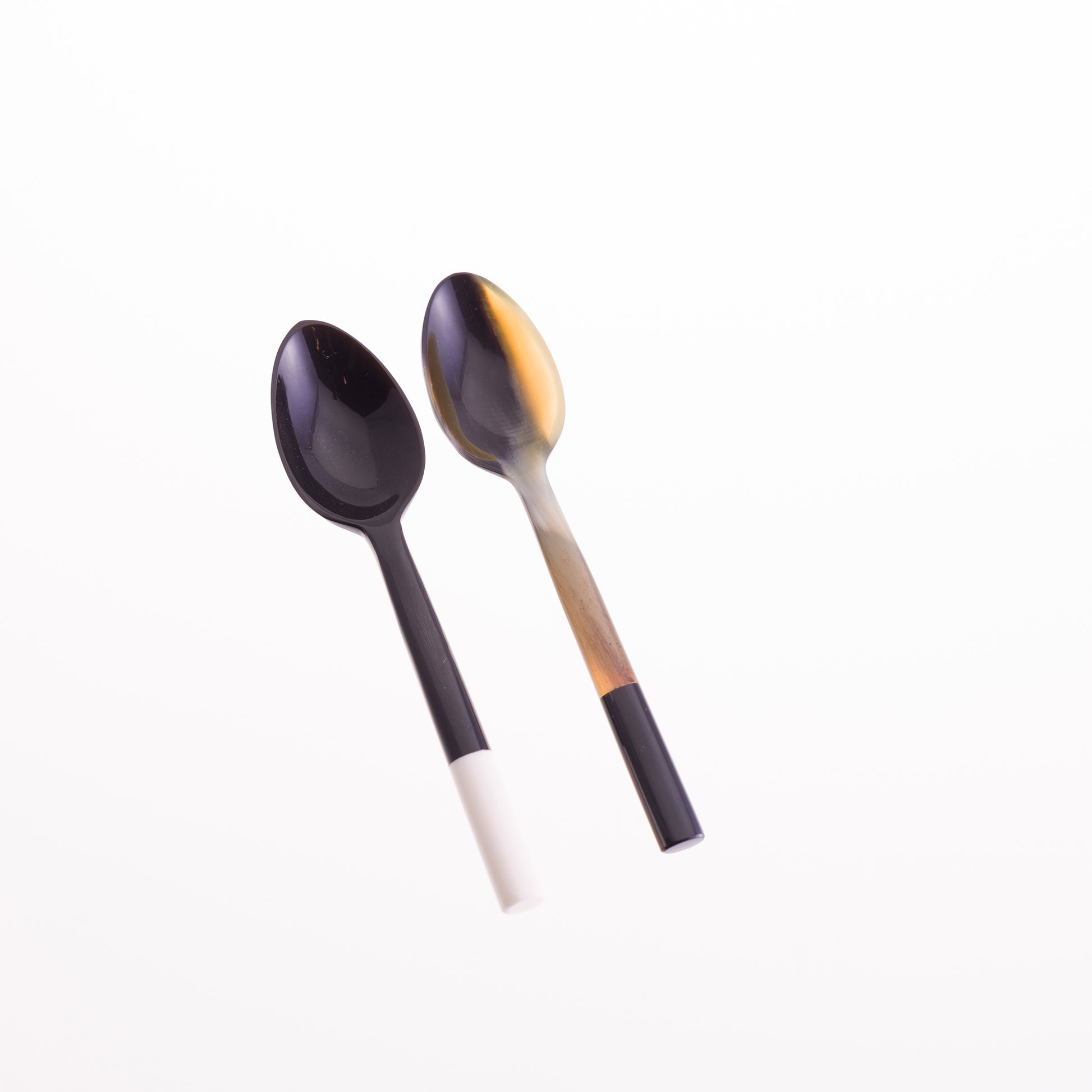 A pair of horn egg spoons. The first is black horn with a white bone tip the second is natural horn with a black tip.