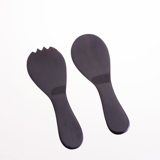 A pair of short handled black water buffalo salad servers designed by Sarah Petherick