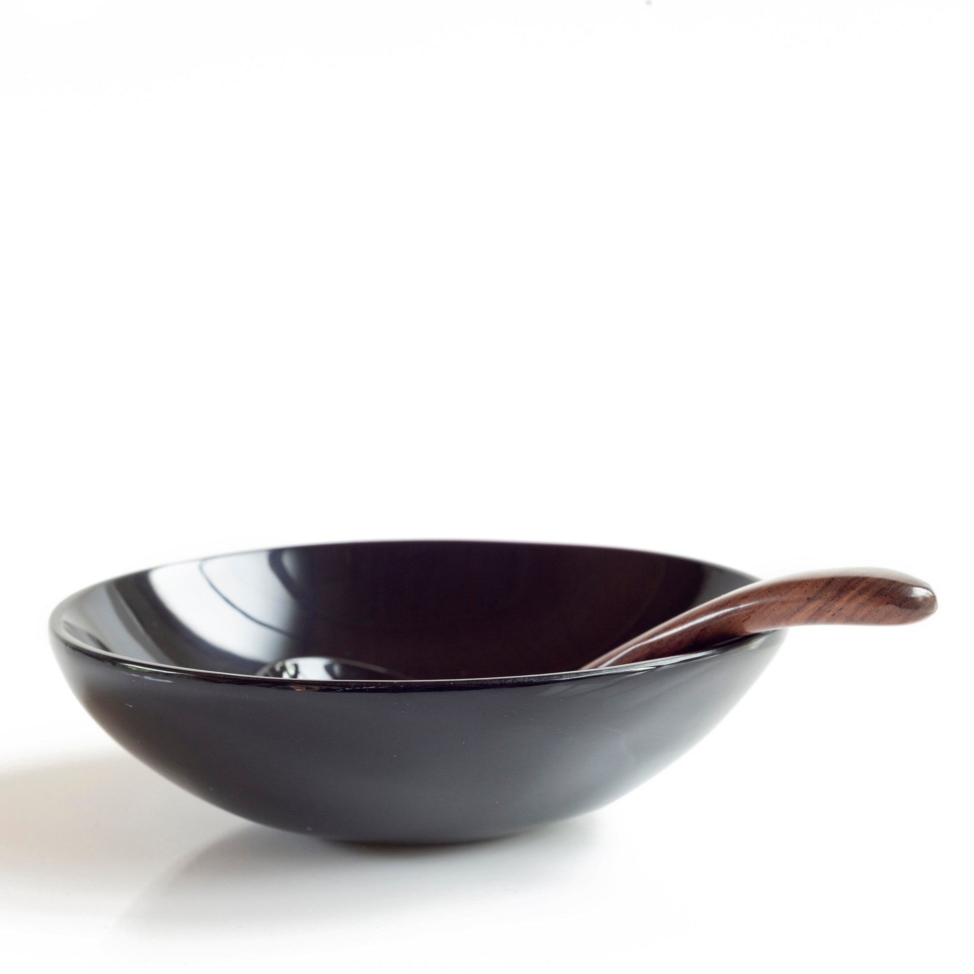 A small ladle made from water buffalo horn with a rosewood handle sitting in a round horn bowl