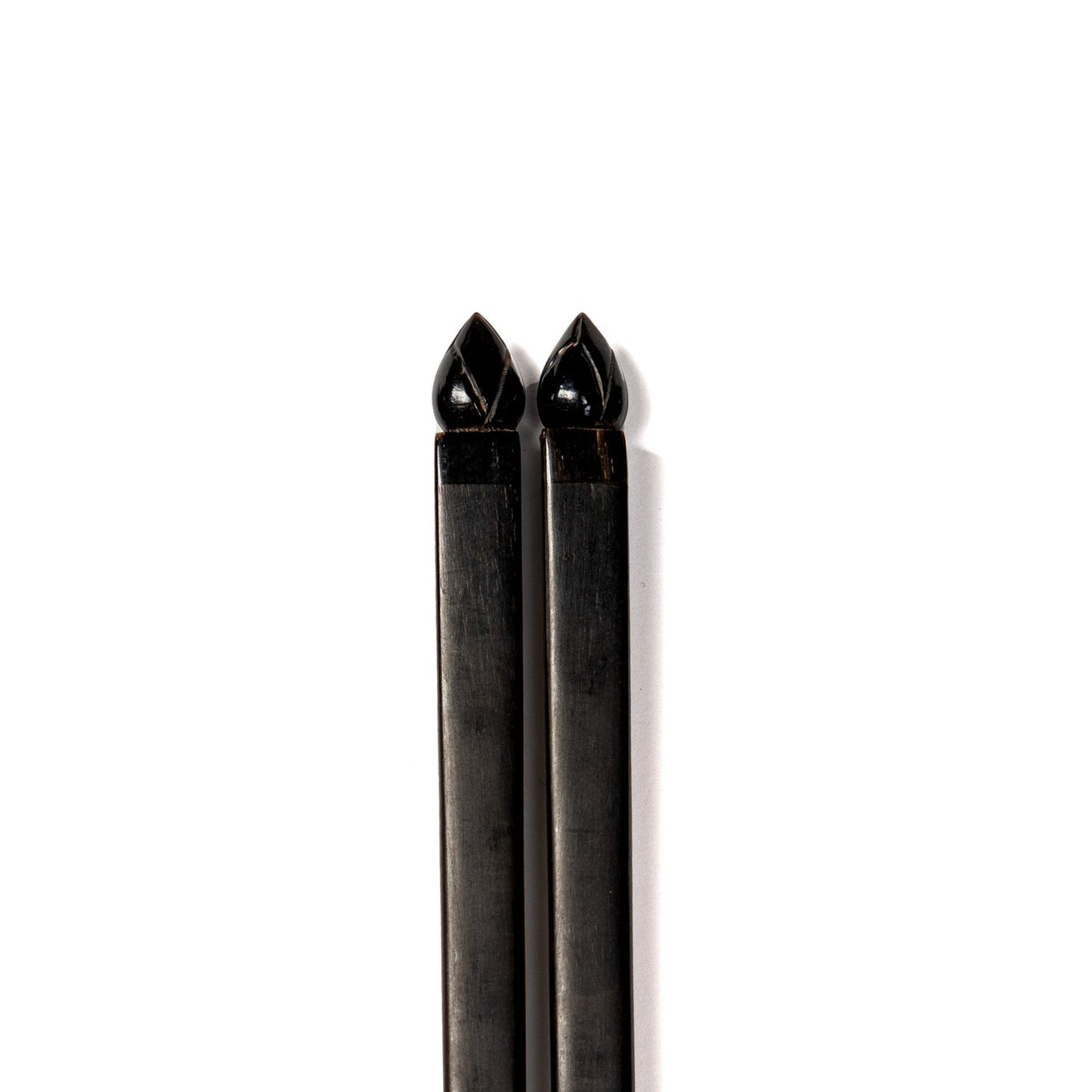 A pair of jet black chopsticks with carved lotus flower detail