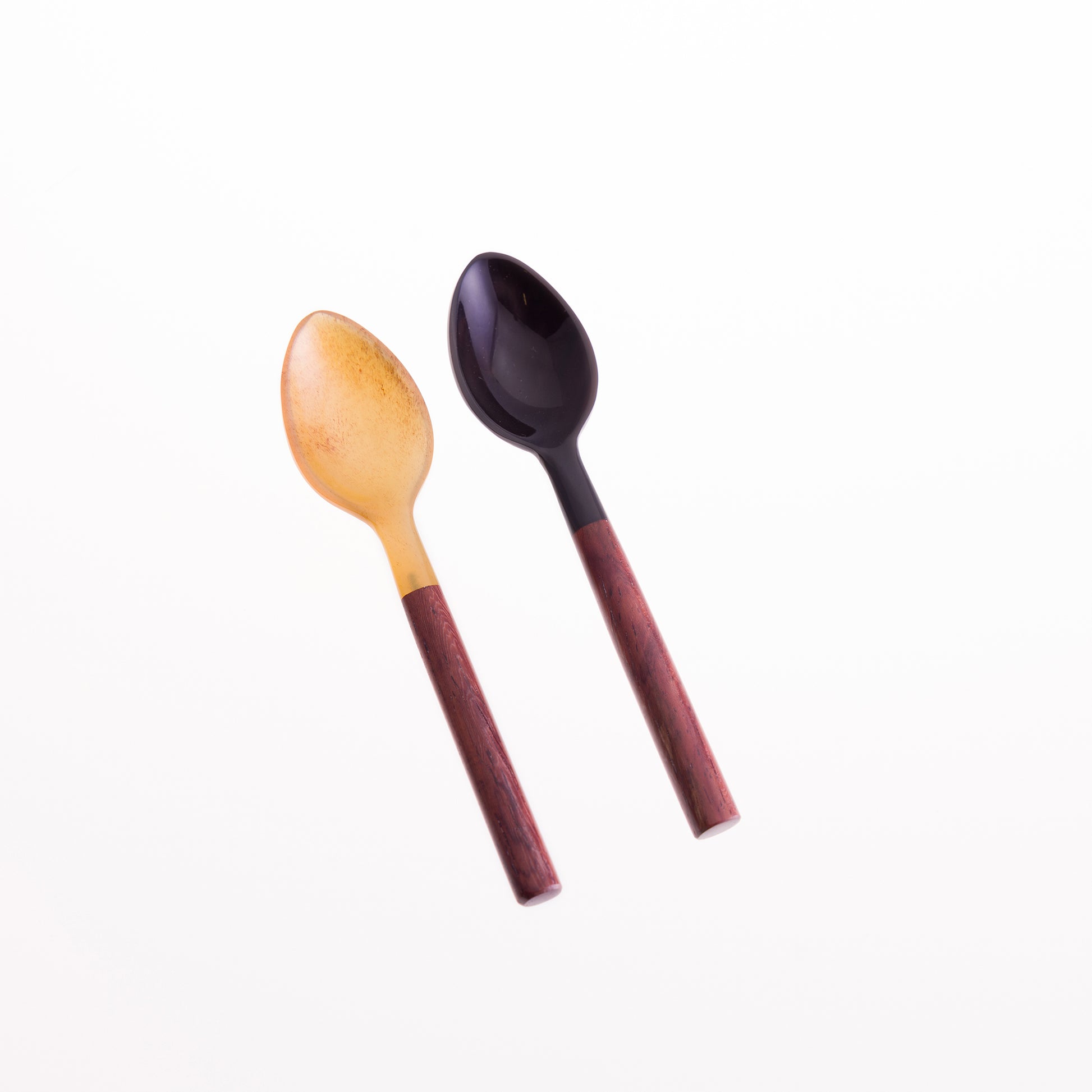 A pair of horn egg spoons. One is natural horn with a rosewood handle, the second is black horn with a rosewood handle